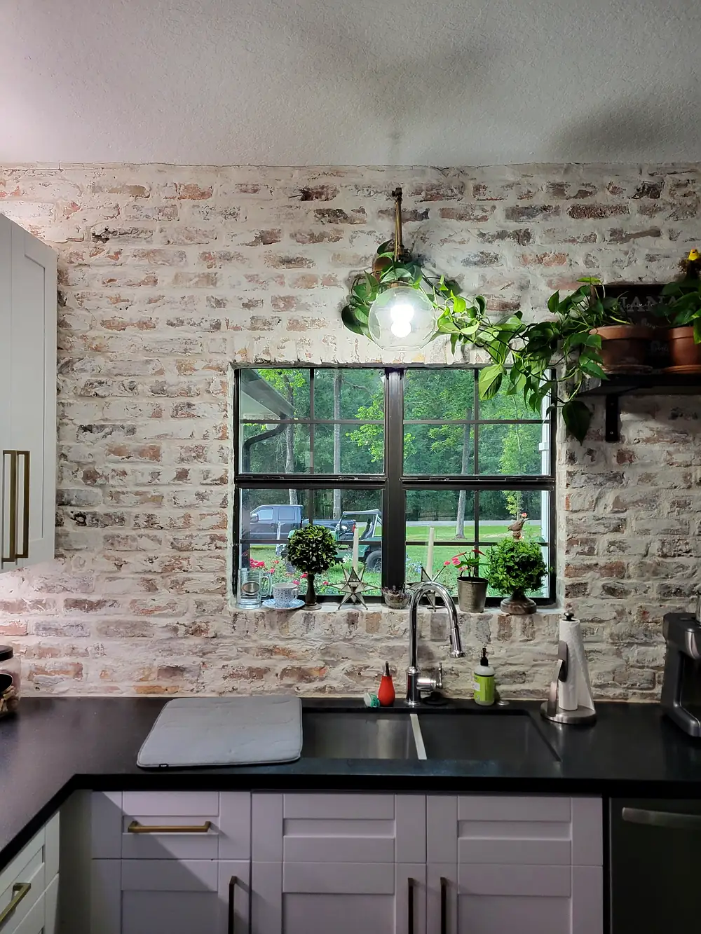 Whitewashed brick wall around a kitchen window above the sink