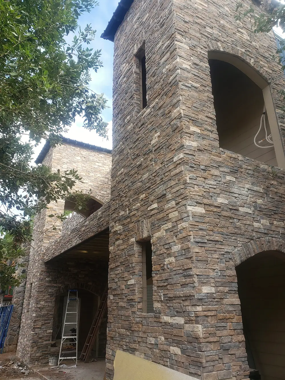 Stone tower with arched balcony openings, clad in stacked stone